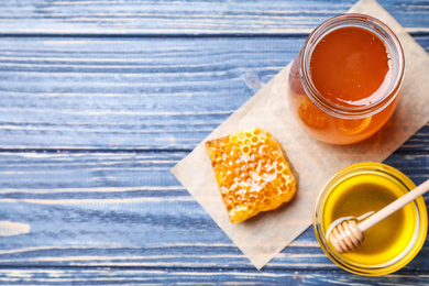 Tasty honey on blue wooden table, flat lay. Space for text