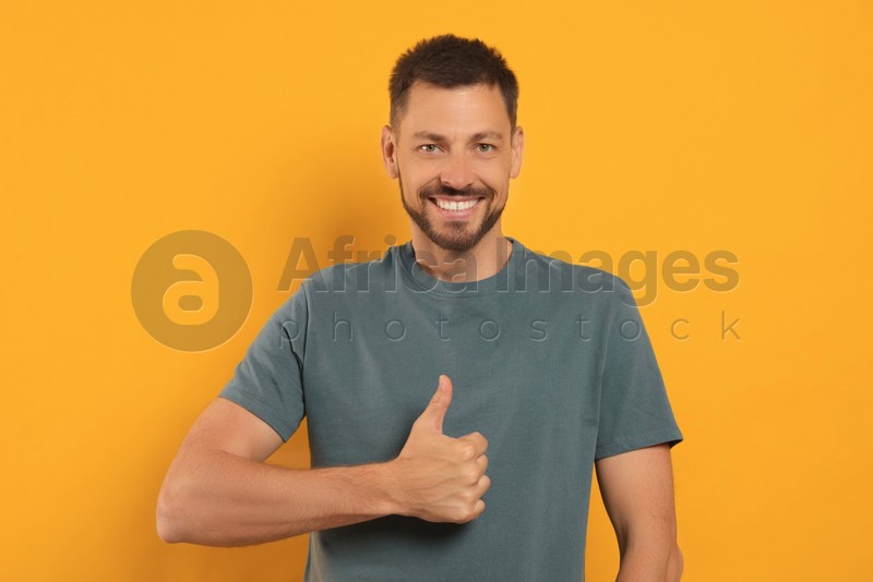 Man showing thumb up on orange background
