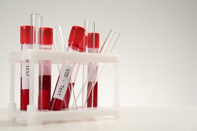 Tubes with blood samples in rack on white table, space for text. STD test