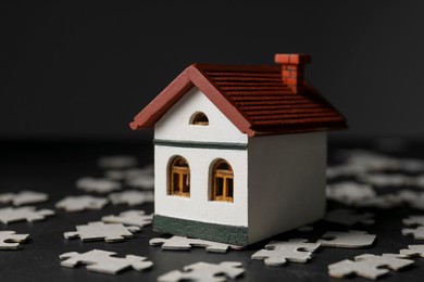 House model and puzzles on black table depicting destruction after earthquake