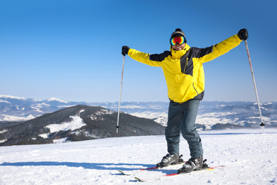 Young man skiing on hill, space for text. Winter vacation