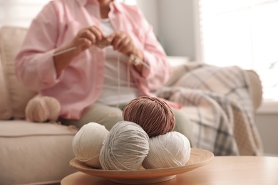 Elderly woman knitting at home, focus on yarn. Creative hobby