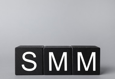 Black cubes with abbreviation SMM (Social media marketing) on grey background