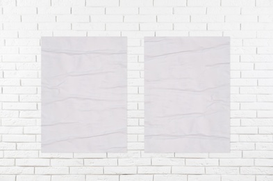 Blank creased posters on white brick wall. Mockup for design 