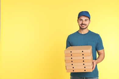 Young courier with pizza boxes on color background, space for text. Food delivery service