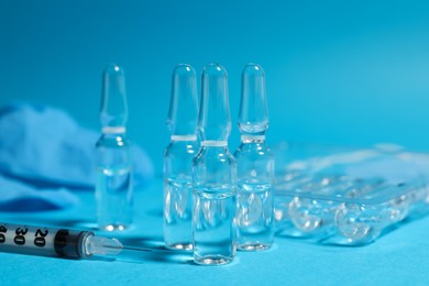 Pharmaceutical ampoules and syringe on light blue background