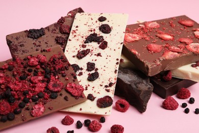 Photo of Different chocolate bars with freeze dried fruits on pink background