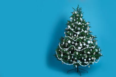 Beautifully decorated Christmas tree on light blue background