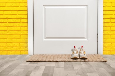 Shoes on door mat in hallway, space for text