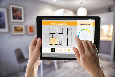 Woman using tablet to set indoor temperature, closeup. Smart home automation system