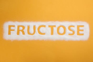 Photo of Word Fructose made of sugar on orange background, top view
