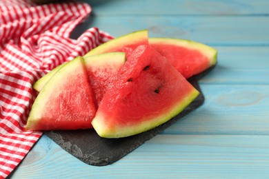 Slate board with slices of juicy watermelon on light blue wooden table