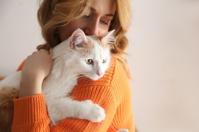 Woman with cute fluffy cat on beige background, closeup