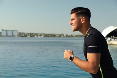 Man wearing modern smart watch during training near river