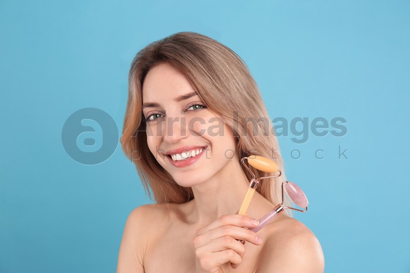 Photo of Young woman with natural face rollers on light blue background