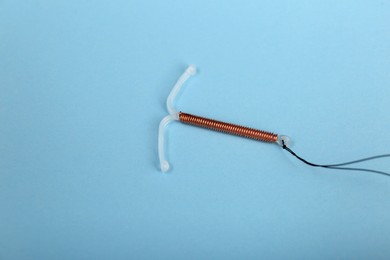 T-shaped intrauterine birth control device on light blue background