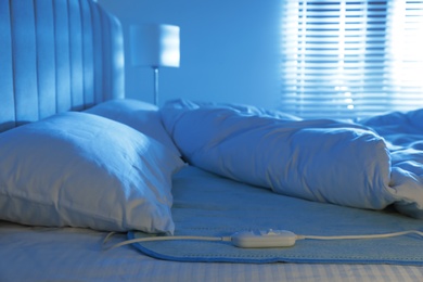 Bed with electric heating pad indoors at night