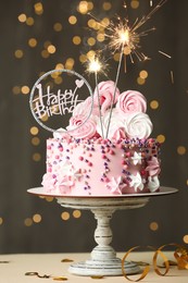 Beautiful birthday cake with festive decor and sparkles on white table