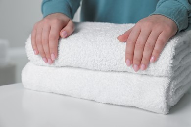 Photo of Woman touching soft white towel indoors, closeup