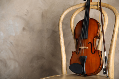 Classic violin and bow on chair against beige background. Space for text