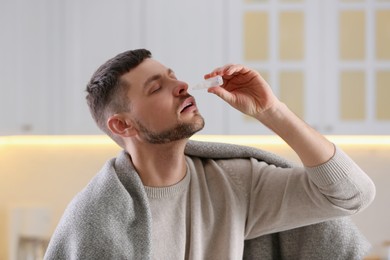 Photo of Ill man using nasal drops at home