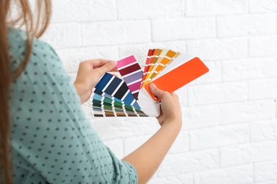 Female interior designer with color palette samples near brick wall, closeup