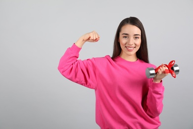 Woman with dumbbell as symbol of girl power on light grey background. 8 March concept