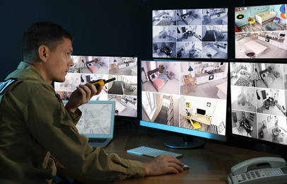 Photo of Security guard with portable transmitter monitoring modern CCTV cameras indoors