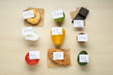 Photo of Food products with calorific value tags on wooden table, flat lay. Weight loss concept