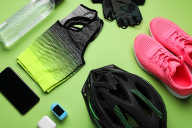 Flat lay composition with different cycling accessories and clothes on green background