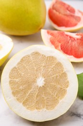 Photo of Different sorts of tasty pomelo fruits on white marble table, closeup