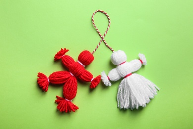 Photo of Traditional martisor shaped as man and woman on green background, top view. Beginning of spring celebration
