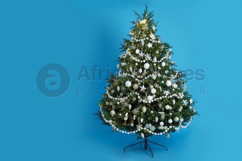 Beautifully decorated Christmas tree on light blue background
