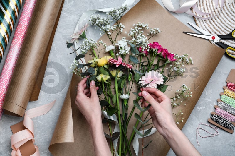 Woman arranging flowers at grey stone table, top view