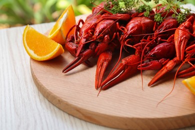 Delicious red boiled crayfish and orange on white wooden table