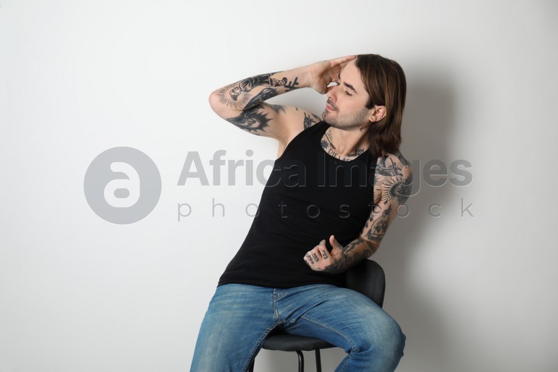 Young man with tattoos on body against white background