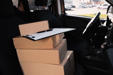 Photo of Clipboard and stacked packages in car, space for text. Courier delivery service