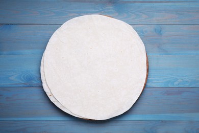 Photo of Delicious thin Armenian lavash on light blue wooden table, top view