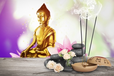 Composition with smoldering incense sticks on wooden table and Buddha figure on background. Space for text