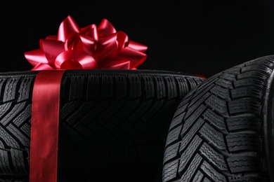Winter tires with red ribbon on black background, closeup
