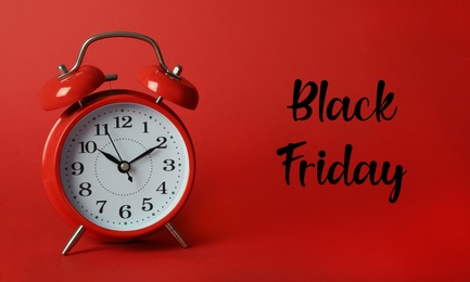 Phrase Black Friday and alarm clock on red background