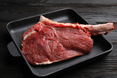 Fresh raw beef cut in baking dish on wooden table, closeup