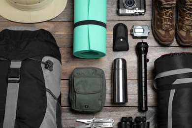 Flat lay composition with backpack and other different camping equipment for tourism on wooden background