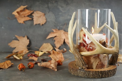 Stylish holder with burning candle and autumn decor on grey stone table. Space for text