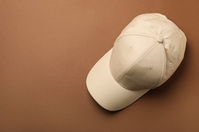 Baseball cap on brown background, top view. Space for text