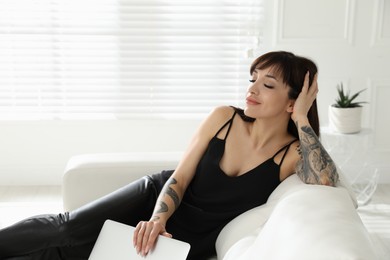 Beautiful woman with tattoos on arms resting in living room