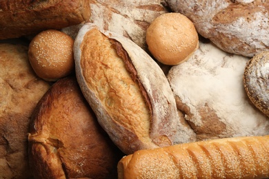 Different kinds of delicious bread as background, top view