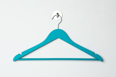Empty turquoise clothes hanger on white wall