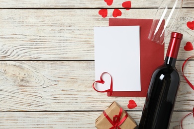 Flat lay composition with blank card on white wooden background, space for text. Valentine's Day celebration