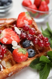 Photo of Delicious Belgian waffles, berries and caramel sauce on table, closeup